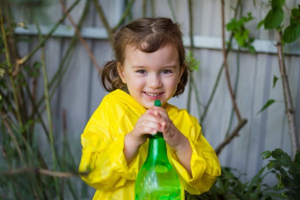На фото – девочка стреляет водой из бутылки с распылителем